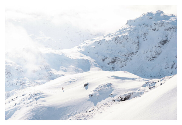 A small figure walking through snowy mountains